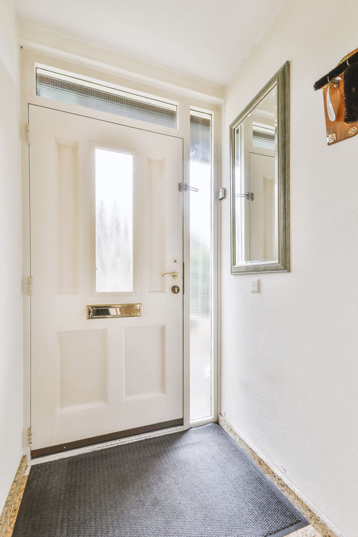 Cream front door with glass panel and side light in a bright hallway