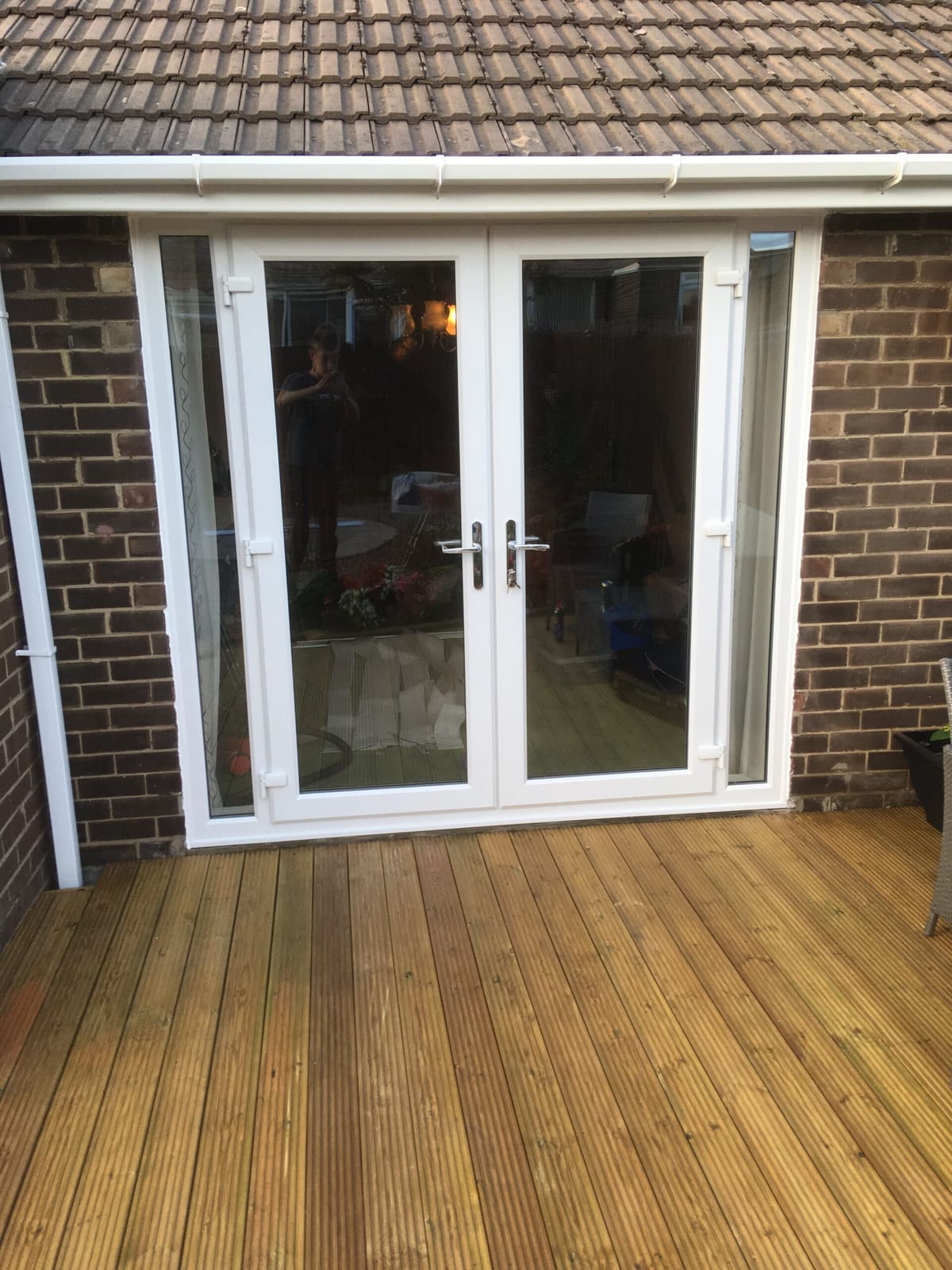 White uPVC French doors opening onto timber decking in Newcastle